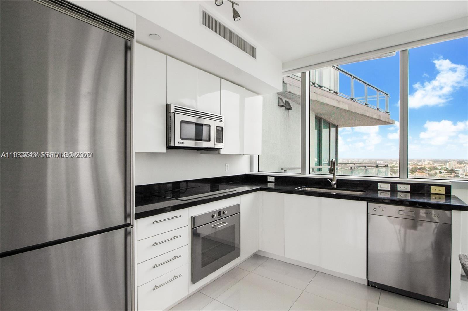 A modern kitchen features white cabinets, black countertops, stainless steel appliances, and floor-to-ceiling windows — 92 SW 3rd St # 2510, Miami FL 33130, MIAMI, FL