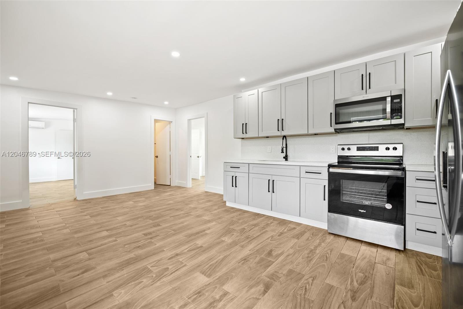 A kitchen features light gray cabinets, stainless steel appliances, and wood-look tile flooring — MIAMI, FL