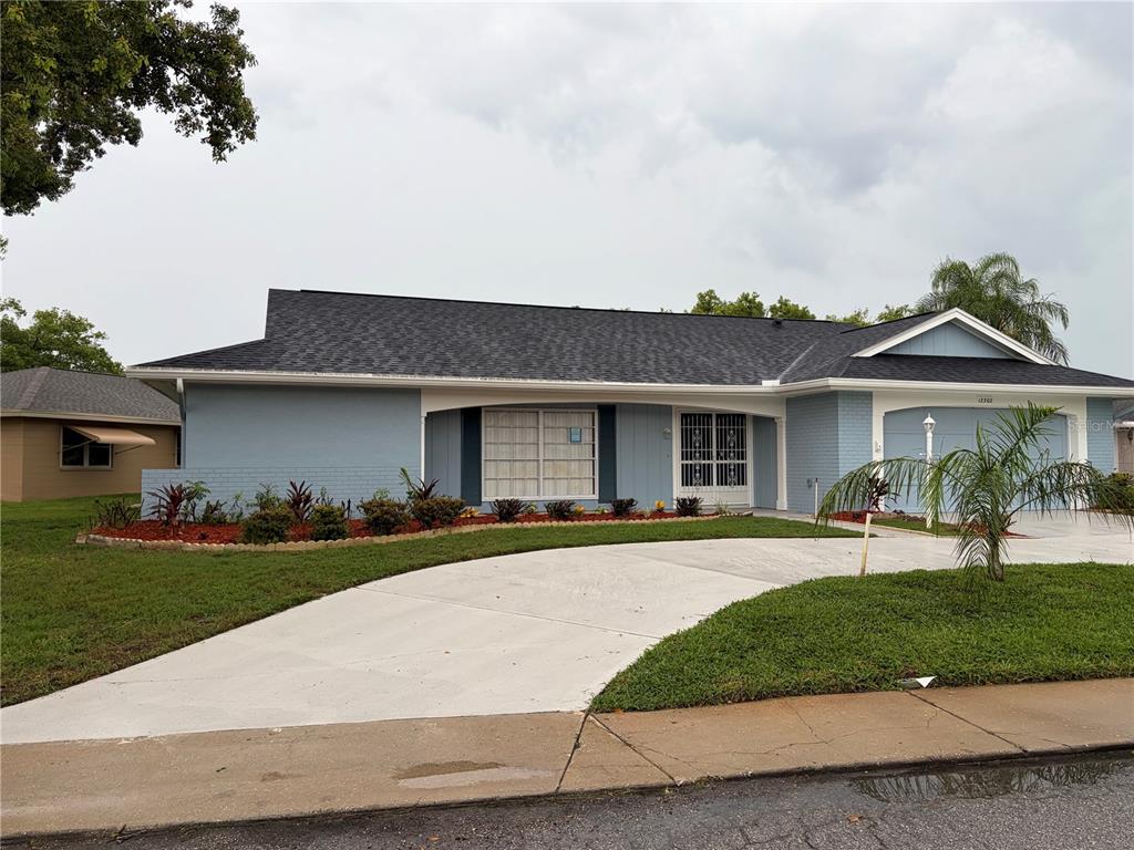 A light blue single-story house features a dark shingled roof and a two-car garage — 12302 FIELDSTONE LANE, HUDSON, FL