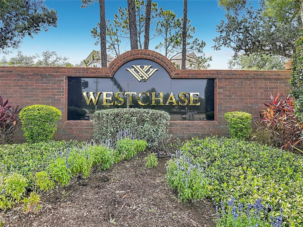 A brick wall features a black sign with the gold text Westchase and a logo — 9502 W PARK VILLAGE DRIVE UNIT 108, TAMPA, FL