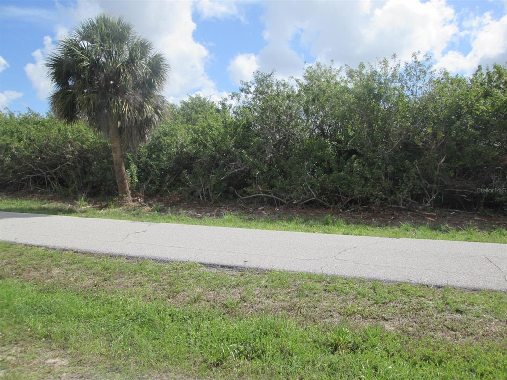 A paved path runs in front of a dense line of trees and shrubs — 6663 & 6669 KEVITT BOULEVARD, PORT CHARLOTTE, FL