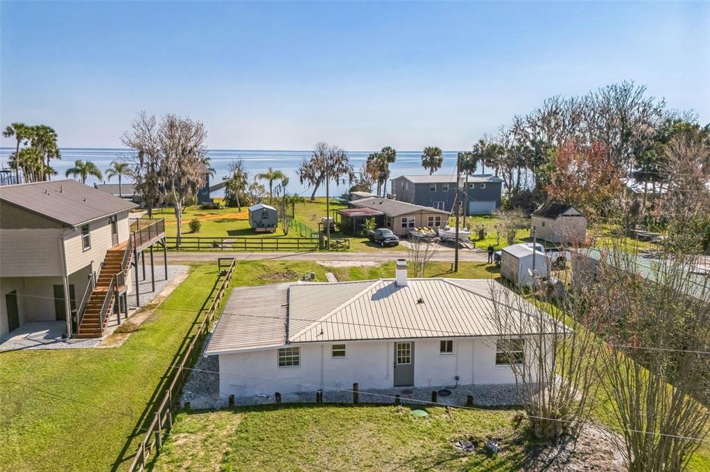 An aerial view shows a white house with a metal roof near a waterfront — 9400 NE 307TH COURT, FORT MC COY, FL