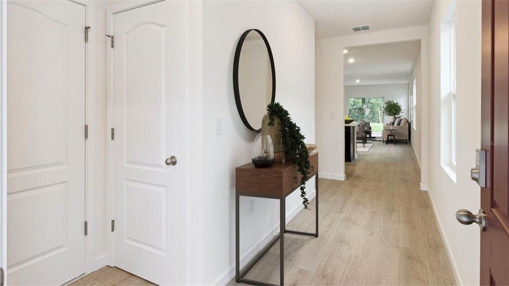 A bright entryway features light wood flooring, a console table with a mirror, and white doors — 1917 HOWARD MESA DRIVE, KISSIMMEE, FL