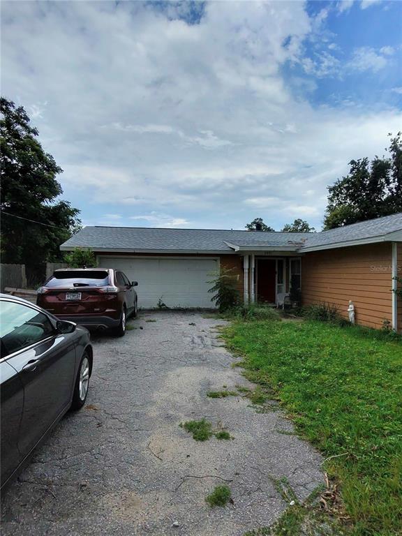 A single-story house with a two-car garage, a gravel driveway, and brown horizontal siding — 3991 SE 19TH AVENUE, OCALA, FL