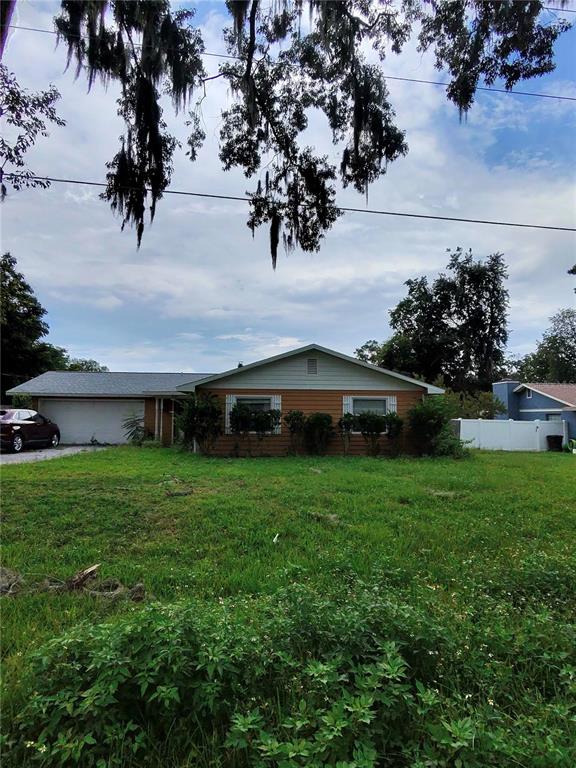 A single-story house with a garage and brown siding sits behind a large grassy yard — 3991 SE 19TH AVENUE, OCALA, FL