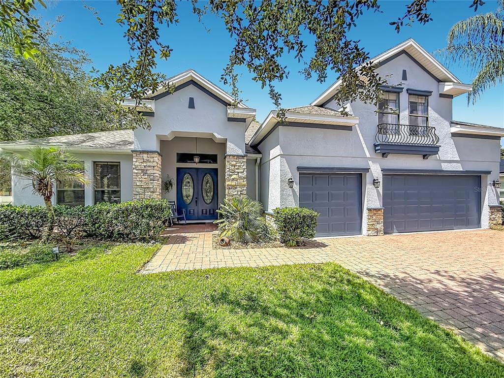 A two-story house with a blue front door, stone accents, and a three-car garage — 204 BUTTER HILL, DELAND, FL
