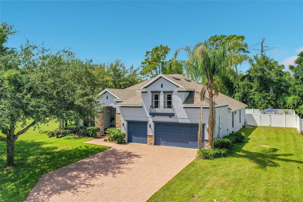 A two-story house with a three-car garage, brick driveway, and a balcony above the garage — 204 BUTTER HILL, DELAND, FL
