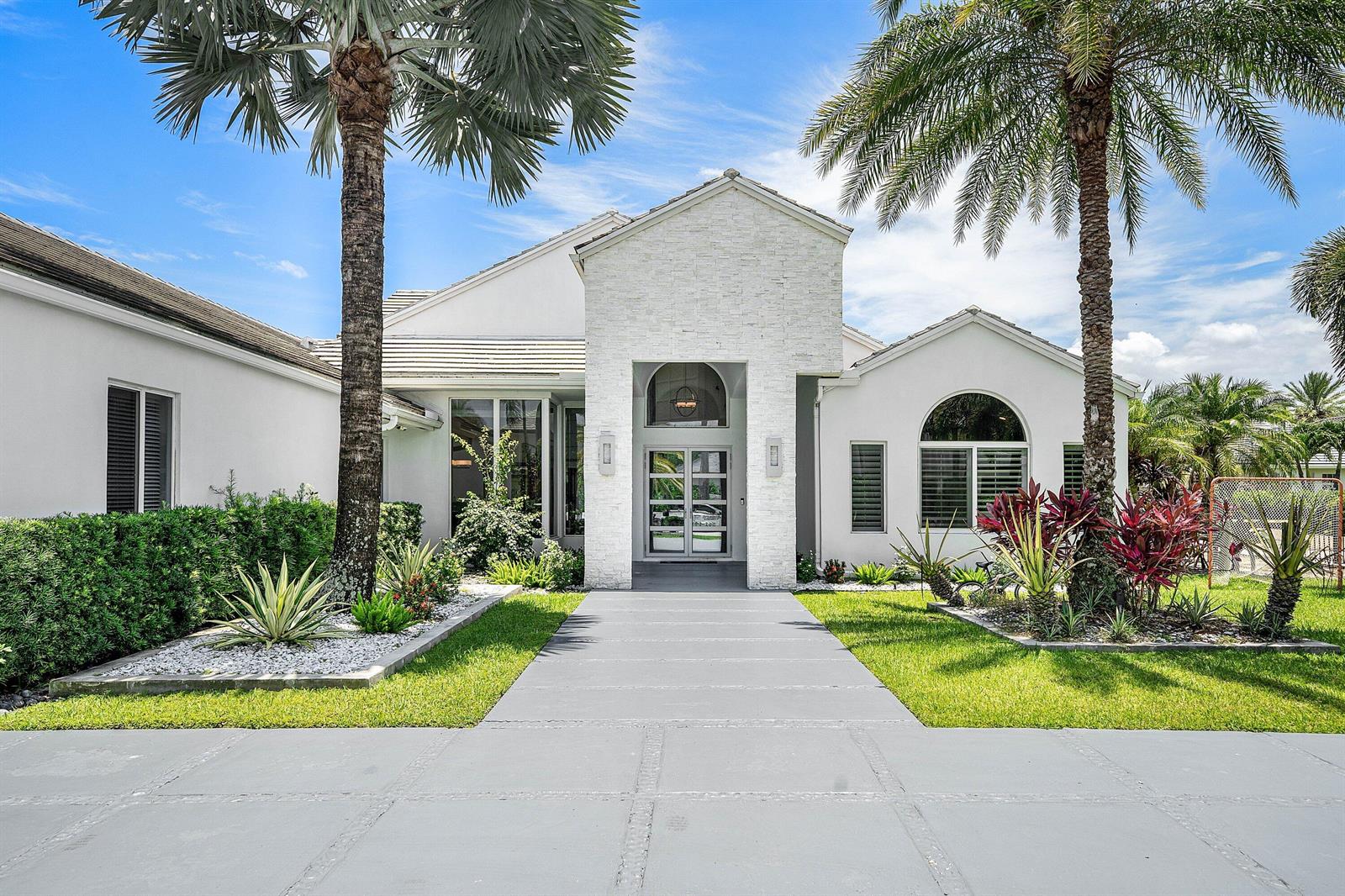 A white house with a stone facade entrance, palm trees, and a concrete walkway — 3828 NW 53rd Street, Boca Raton FL 33496, BOCA RATON, FL