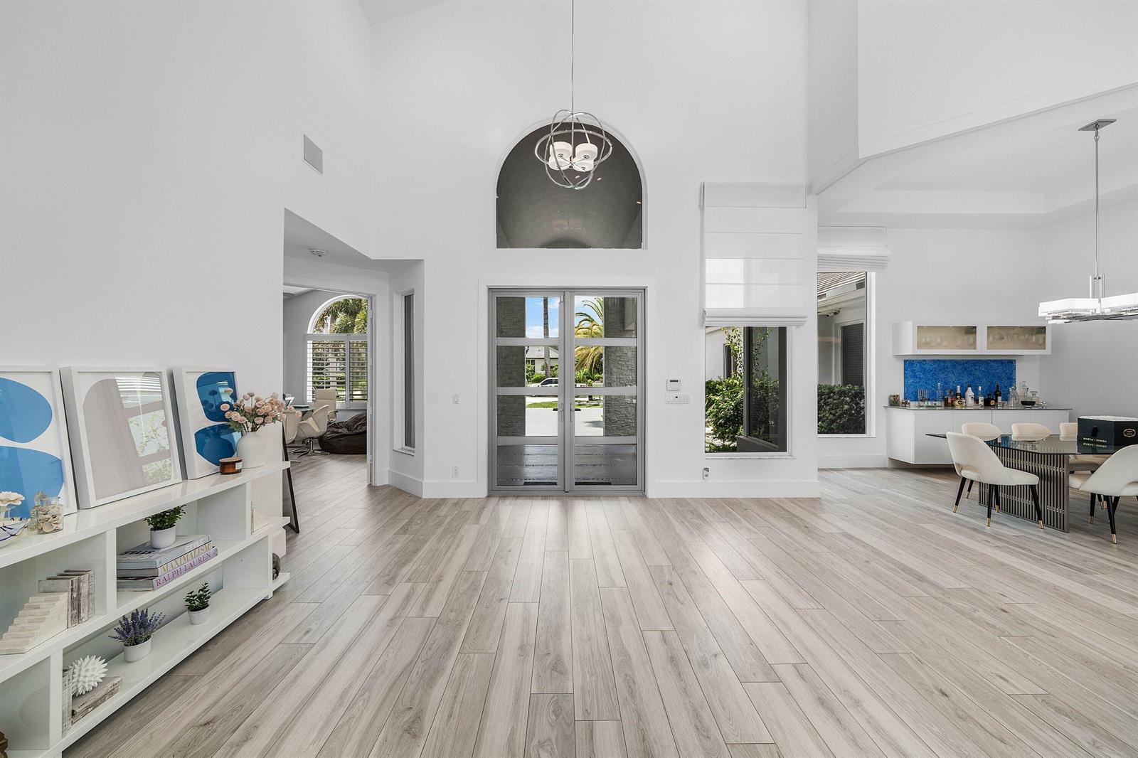 A bright, open-concept foyer with high ceilings, light wood-look flooring, and a glass-paneled double door — 3828 NW 53rd Street, Boca Raton FL 33496, BOCA RATON, FL