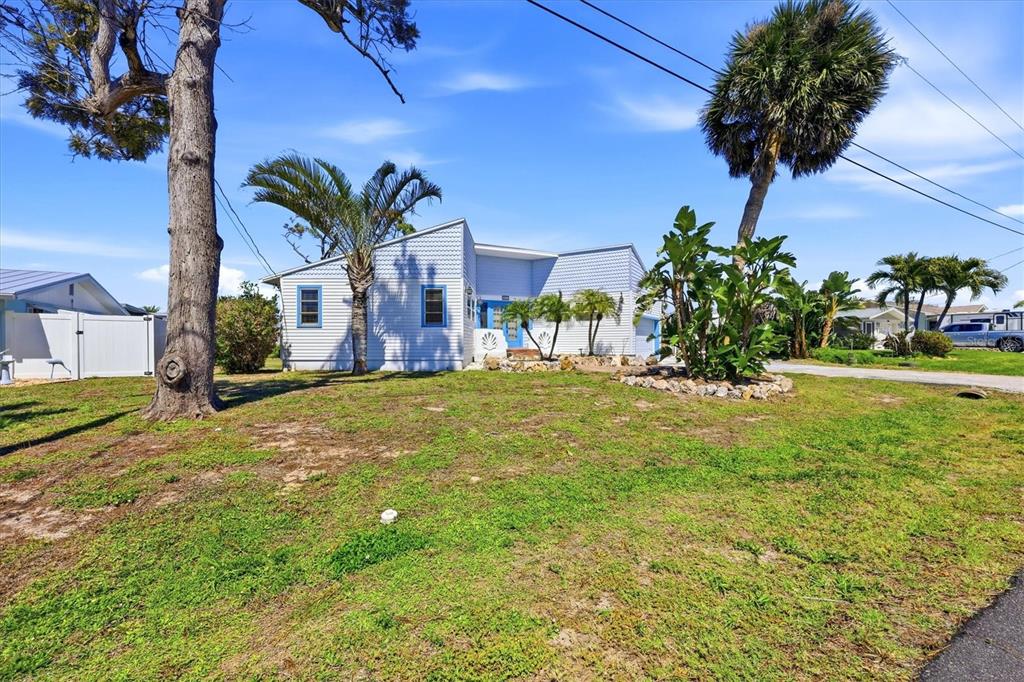 A light blue house with a blue front door sits behind a grassy yard — 1052 KANT STREET, ENGLEWOOD, FL