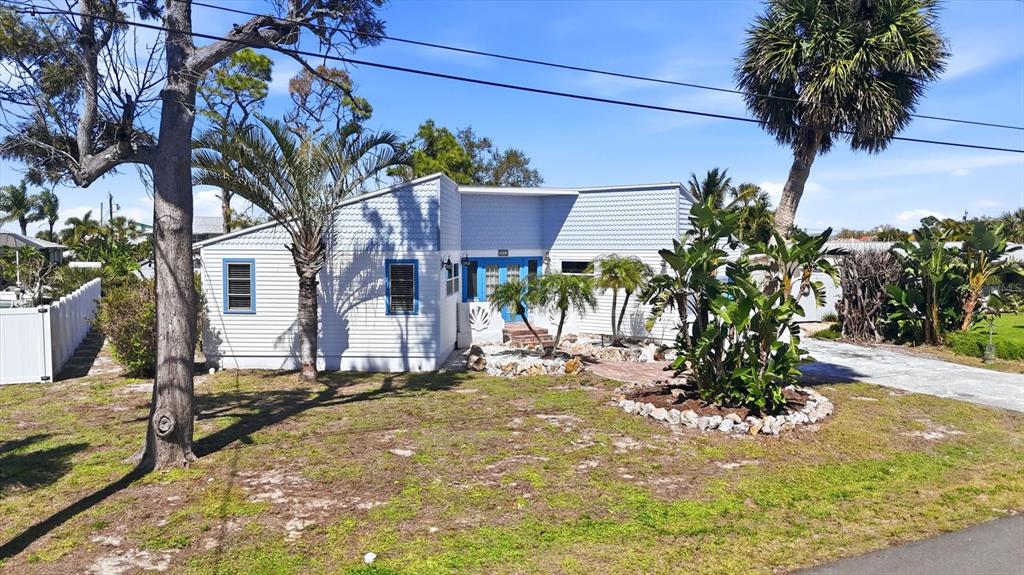 A light blue, single-story house with a front entrance and tropical landscaping — 1052 KANT STREET, ENGLEWOOD, FL
