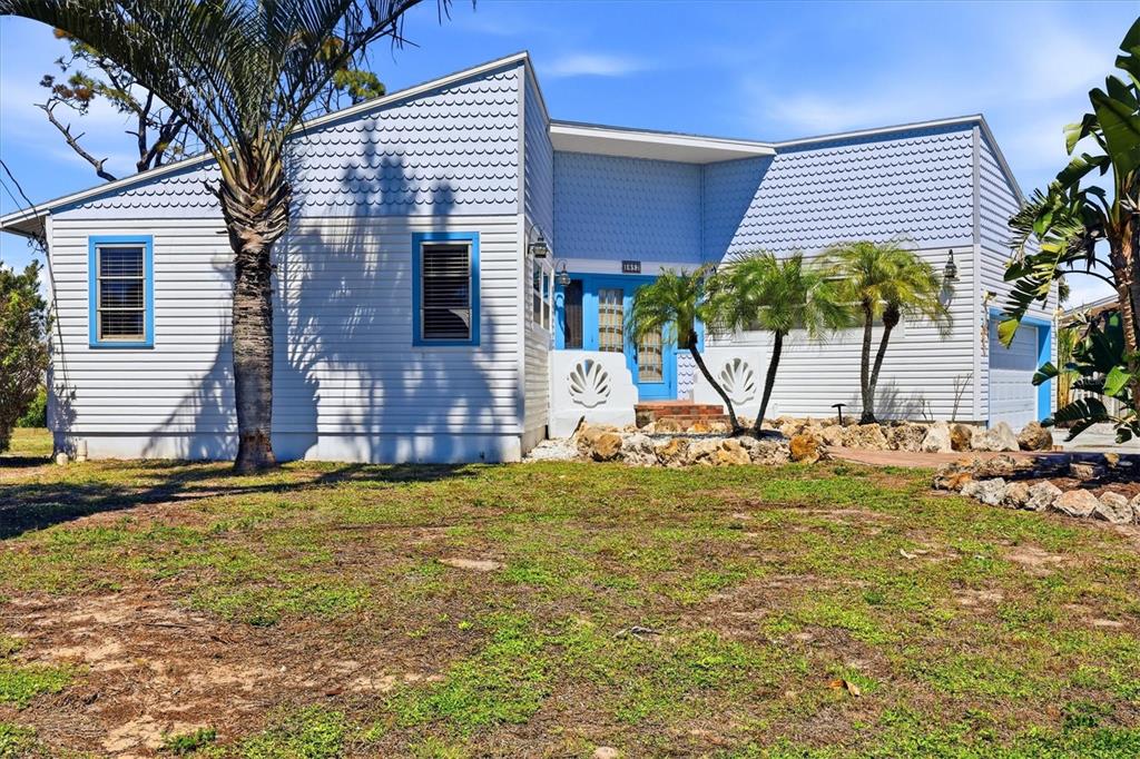 A light blue house with horizontal and scalloped siding features a front entrance and palms — 1052 KANT STREET, ENGLEWOOD, FL
