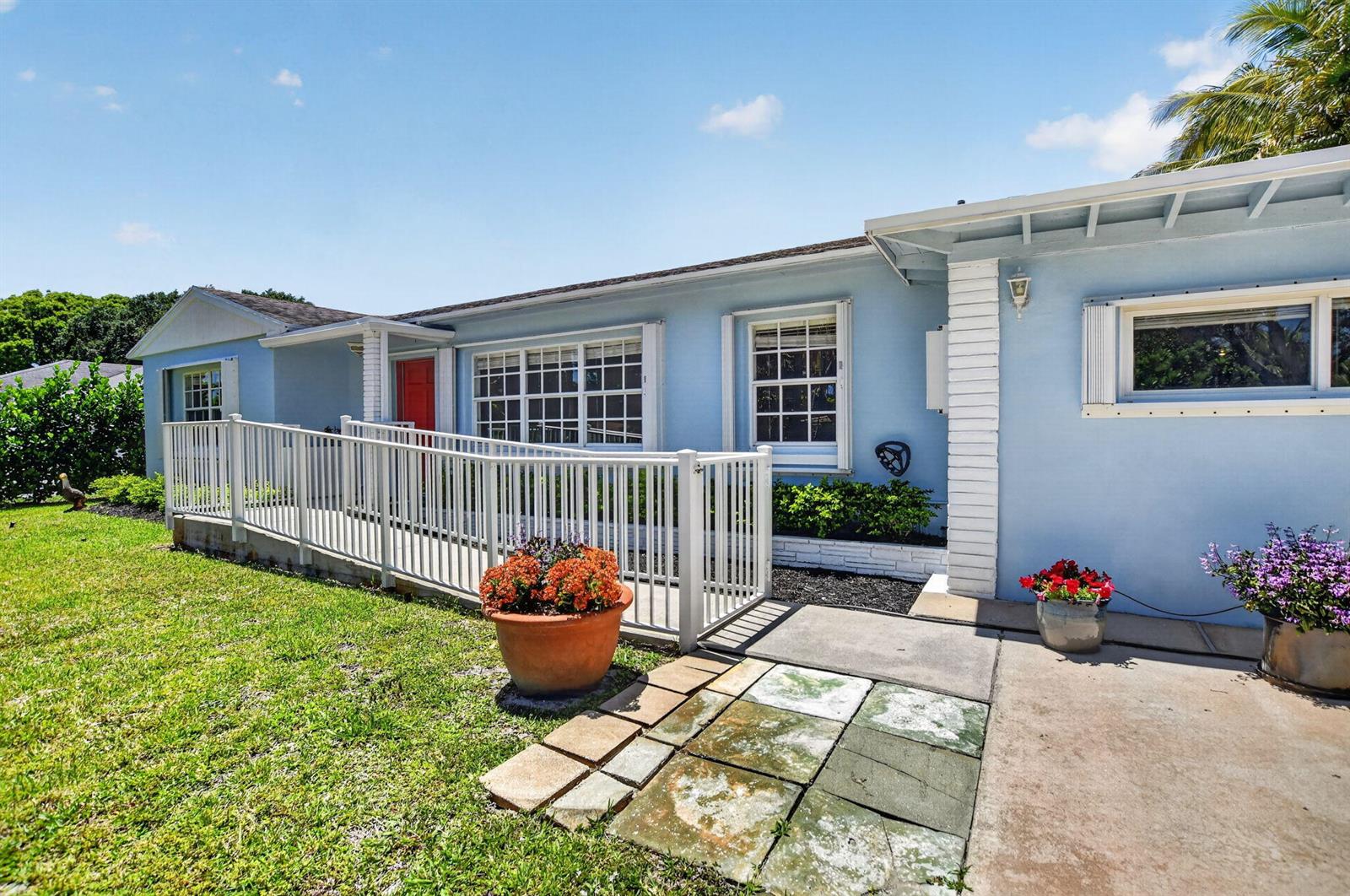 A light blue house exterior features a white wheelchair ramp leading to a red door — 277 NW 3rd Court, Boca Raton FL 33432, BOCA RATON, FL