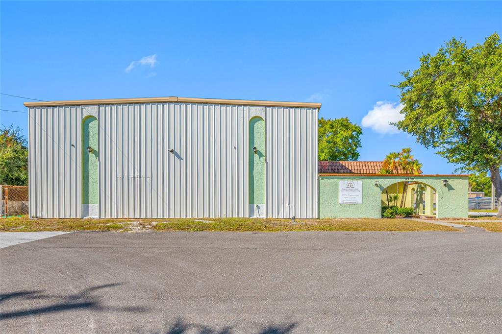 A metal-sided commercial building with a stucco entrance and arched entryway under a blue sky — 5802 N OCCIDENT STREET, TAMPA, FL