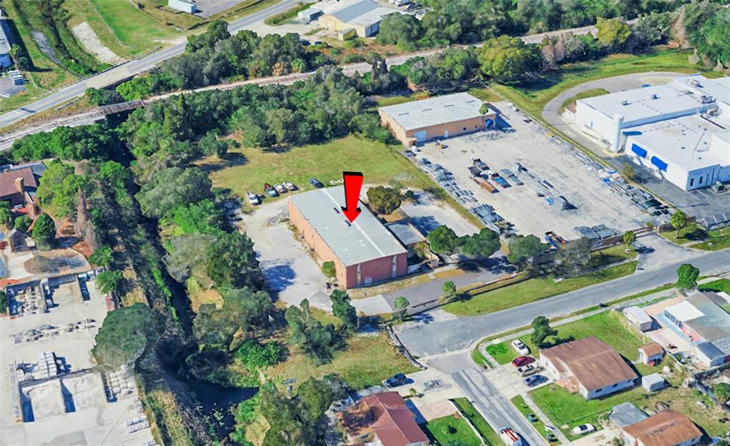 An aerial view shows a rectangular industrial building with a red arrow pointing toward it — 5802 N OCCIDENT STREET, TAMPA, FL
