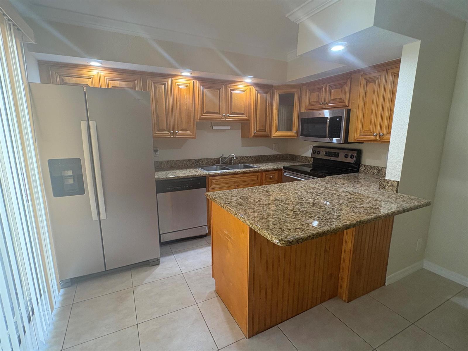 A kitchen features wood cabinets, granite countertops, stainless steel appliances, and tile flooring — 234 Lake Arbor Drive, Palm Springs FL 33461, PALM SPRINGS, FL