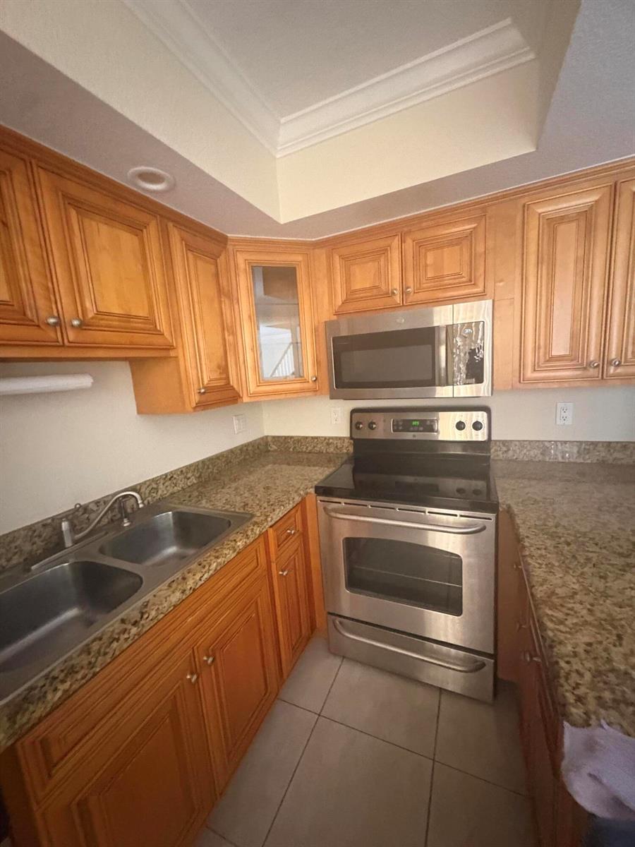 A kitchen with wood cabinets, granite countertops, stainless steel appliances, and tile flooring — 234 Lake Arbor Drive, Palm Springs FL 33461, PALM SPRINGS, FL