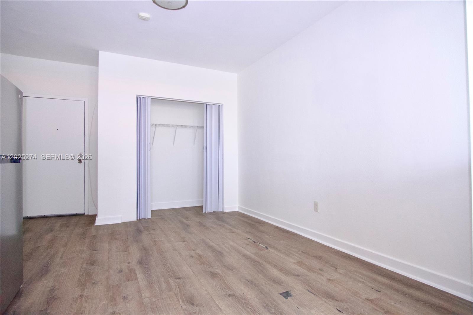 An empty room features light wood-look flooring, white walls, and a small closet with folding doors — 501 SW 6th Ct # 213, Miami FL 33130, MIAMI, FL