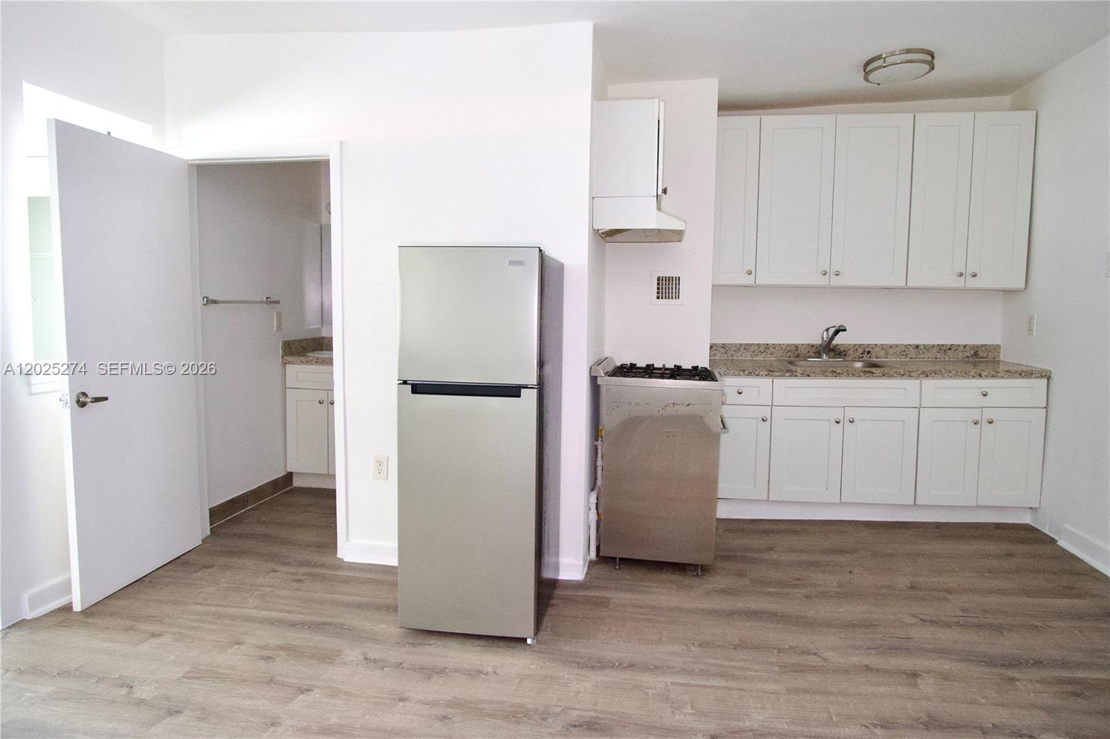 A small kitchen features white cabinets, stainless steel appliances, and light wood-look flooring — 501 SW 6th Ct # 213, Miami FL 33130, MIAMI, FL