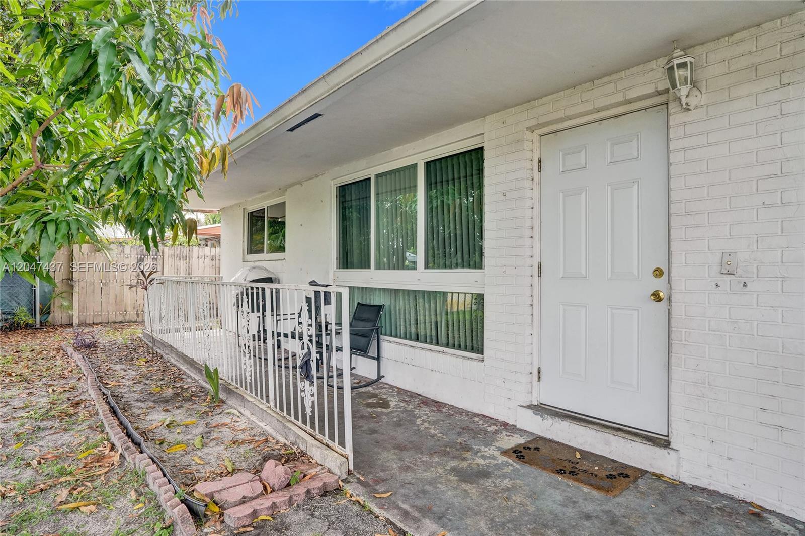 A white brick house exterior features a concrete porch with a metal railing — 6358 SW 20th Ct, Miramar FL 33023, MIRAMAR, FL