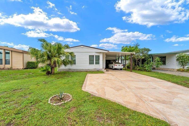 A white single-story manufactured home features a large stone driveway and a palm tree — 9001 SHELDON WEST DRIVE, TAMPA, FL