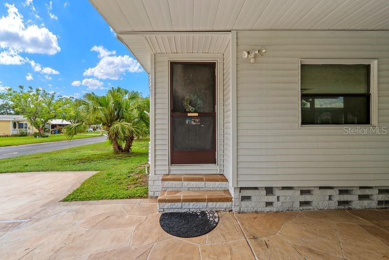 A covered porch with stone flooring leads to a front door with a screen — 9001 SHELDON WEST DRIVE, TAMPA, FL