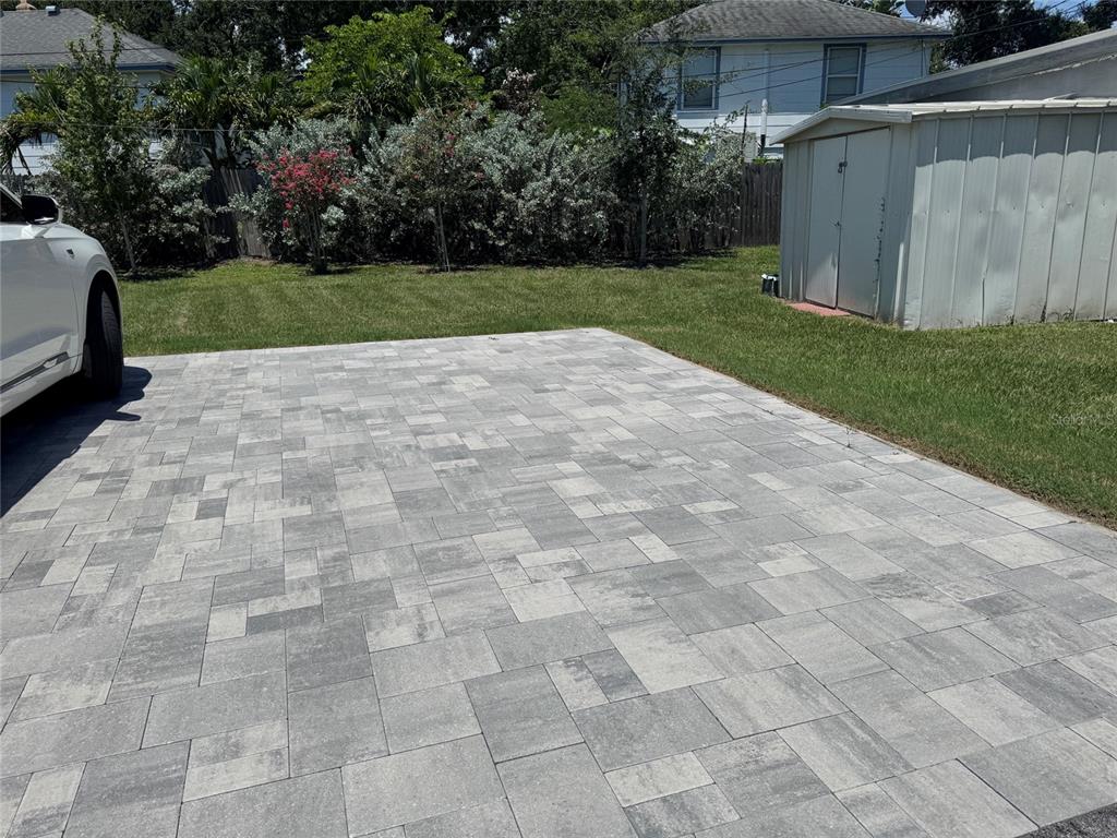 A paved driveway sits next to a grassy lawn and a metal storage shed — 2845 9TH AVENUE N, ST PETERSBURG, FL