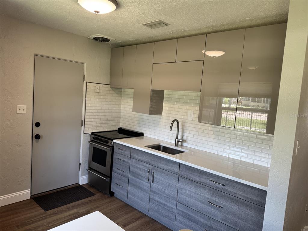 A kitchen features gray wood-grain lower cabinets, glossy beige upper cabinets, and a white backsplash — 2845 9TH AVENUE N, ST PETERSBURG, FL