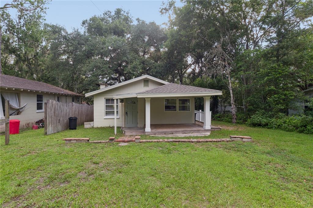 A small, light-colored house features a covered front porch and a low brick garden border — 247 N LEMON AVENUE, BROOKSVILLE, FL