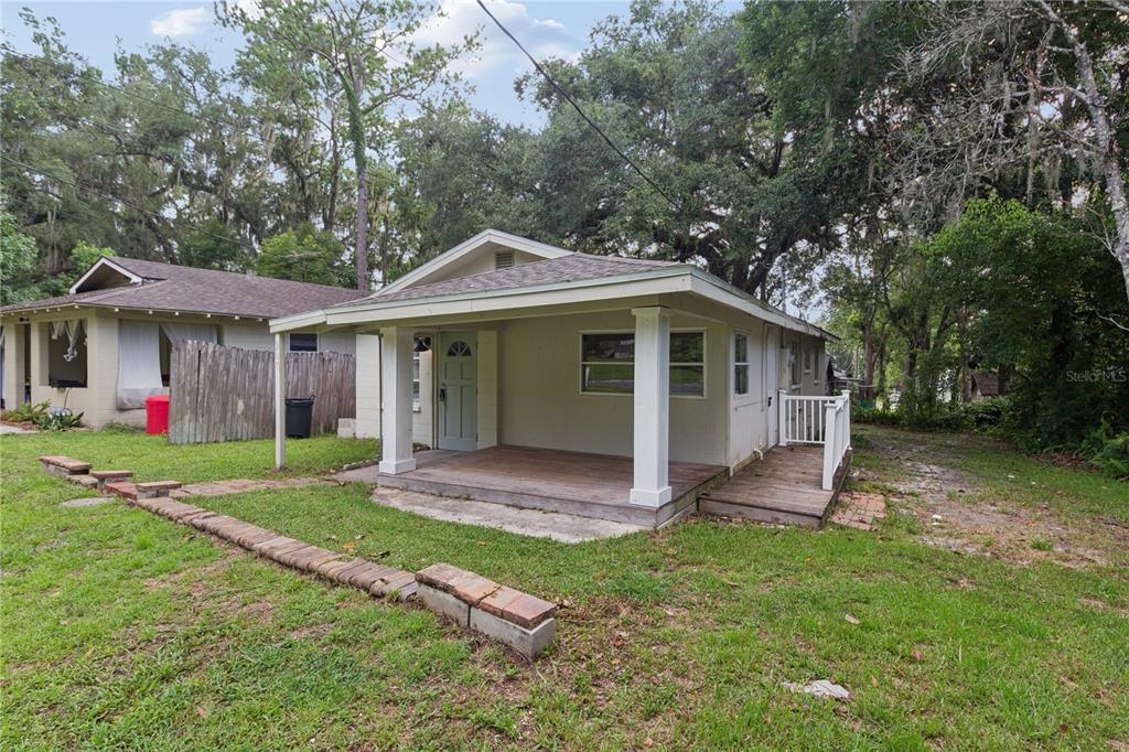 A small, light-colored house features a covered front porch with white columns and wooden decking — 247 N LEMON AVENUE, BROOKSVILLE, FL