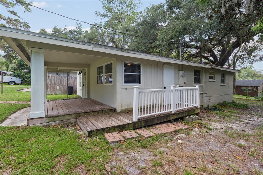 A wooden deck with a white railing sits beside the exterior of a beige house — 247 N LEMON AVENUE, BROOKSVILLE, FL