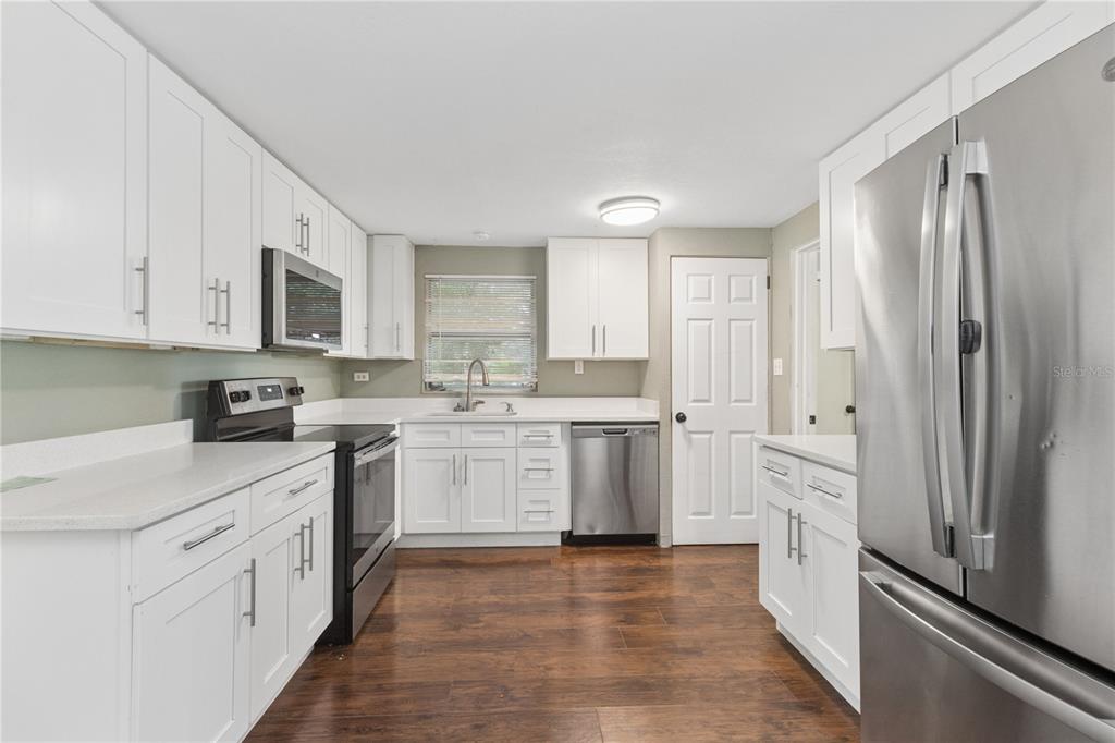 A kitchen with white cabinets, stainless steel appliances, quartz countertops, and dark wood flooring — 247 N LEMON AVENUE, BROOKSVILLE, FL