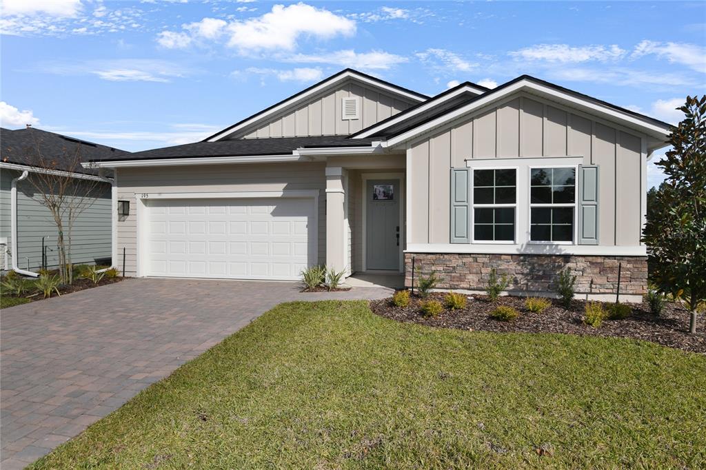 A single-story house features a two-car garage, stone veneer accents, and light-colored vertical siding — 195 ENCLAVE AVENUE, PALM COAST, FL