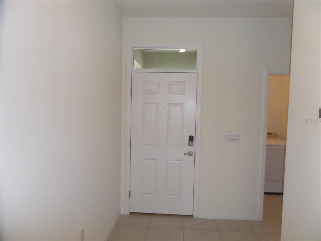 A white front door with a transom window sits in a room with tiled flooring — 5059 STOKES WAY, WILDWOOD, FL