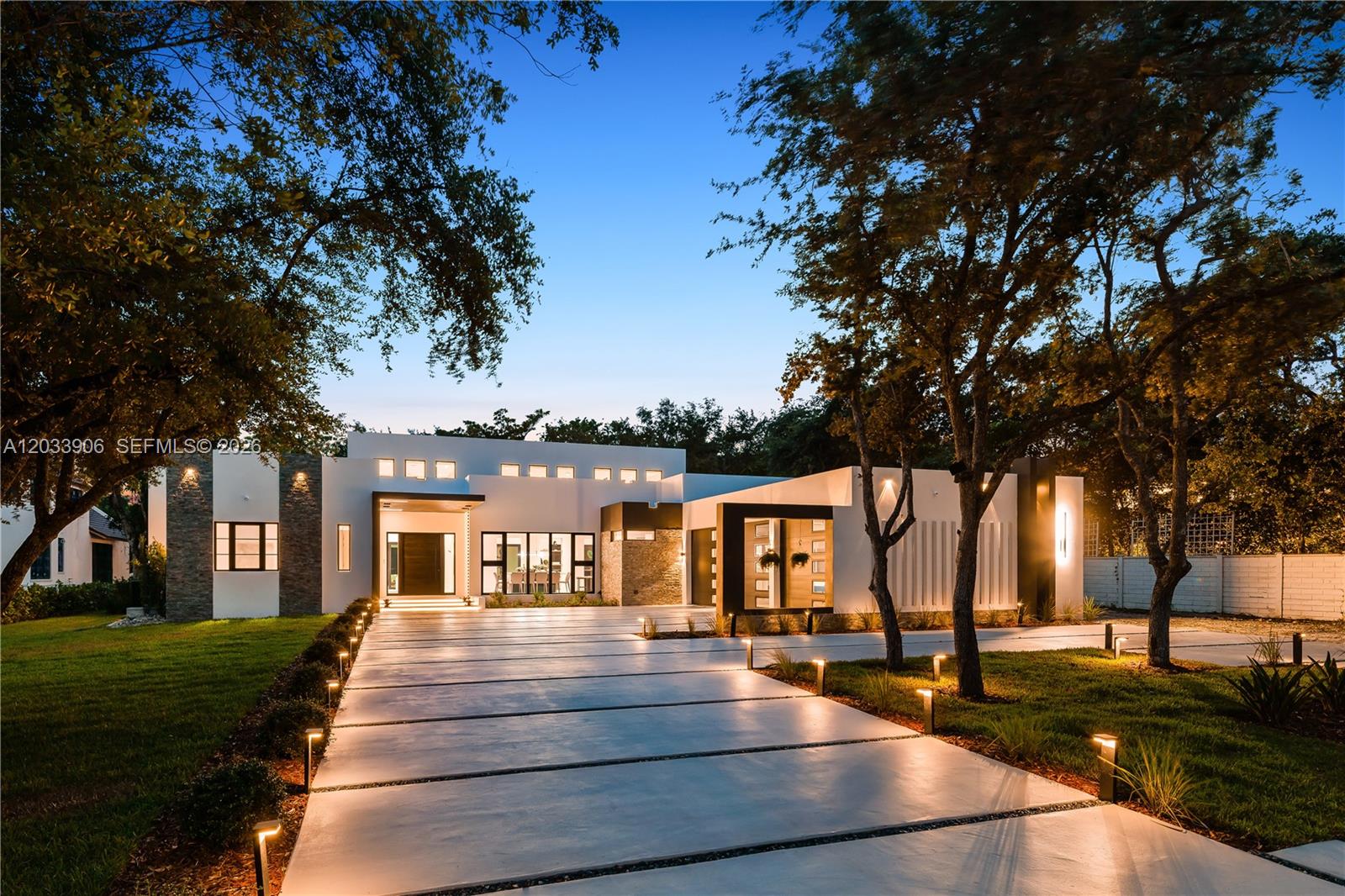 A modern, single-story white house with a paved driveway and landscape lighting at dusk — 6200 SW 83 Av, Miami FL 33143, MIAMI, FL