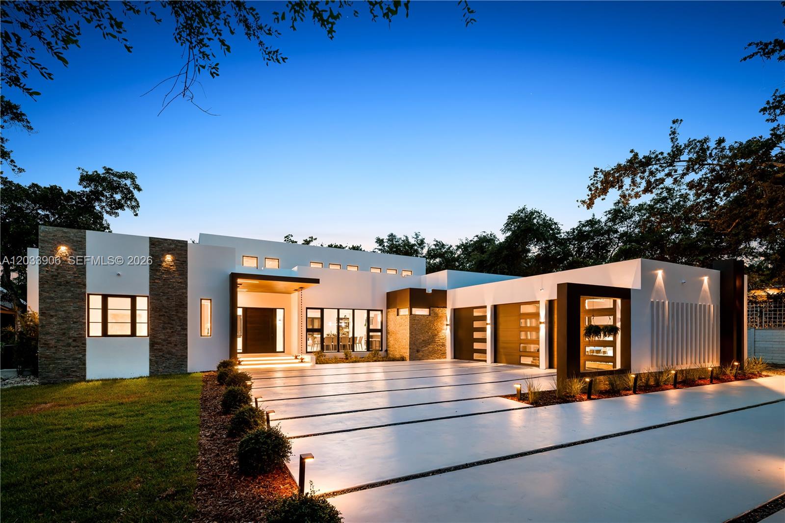 A modern, single-story house with a stone facade, flat roof, and illuminated concrete driveway — 6200 SW 83 Av, Miami FL 33143, MIAMI, FL