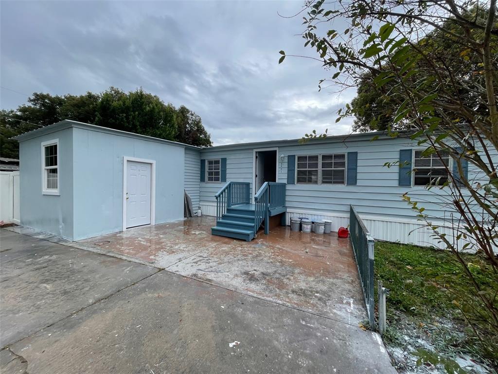A light blue mobile home features a concrete patio, blue stairs, and a side shed — 4421 TODD AVENUE, ORLANDO, FL