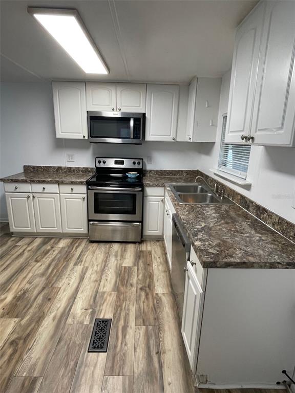 A kitchen features white cabinets, stainless steel appliances, and dark laminate countertops — 4421 TODD AVENUE, ORLANDO, FL