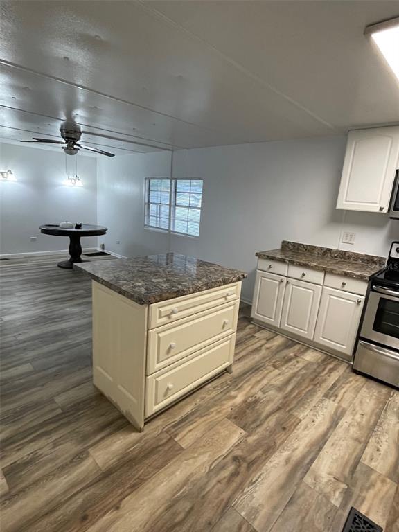 A kitchen features a portable island, white cabinets, granite-look countertops, and wood-look flooring — 4421 TODD AVENUE, ORLANDO, FL