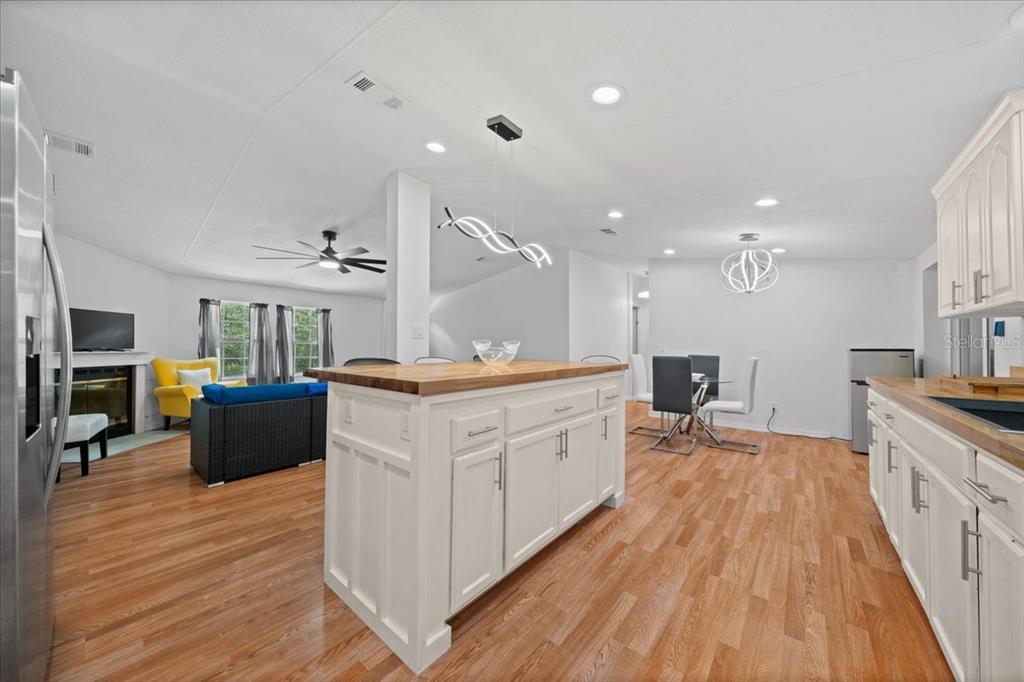 An open-concept kitchen and living area featuring a white island, wood flooring, and recessed lighting — 13120 SW 90TH STREET, DUNNELLON, FL