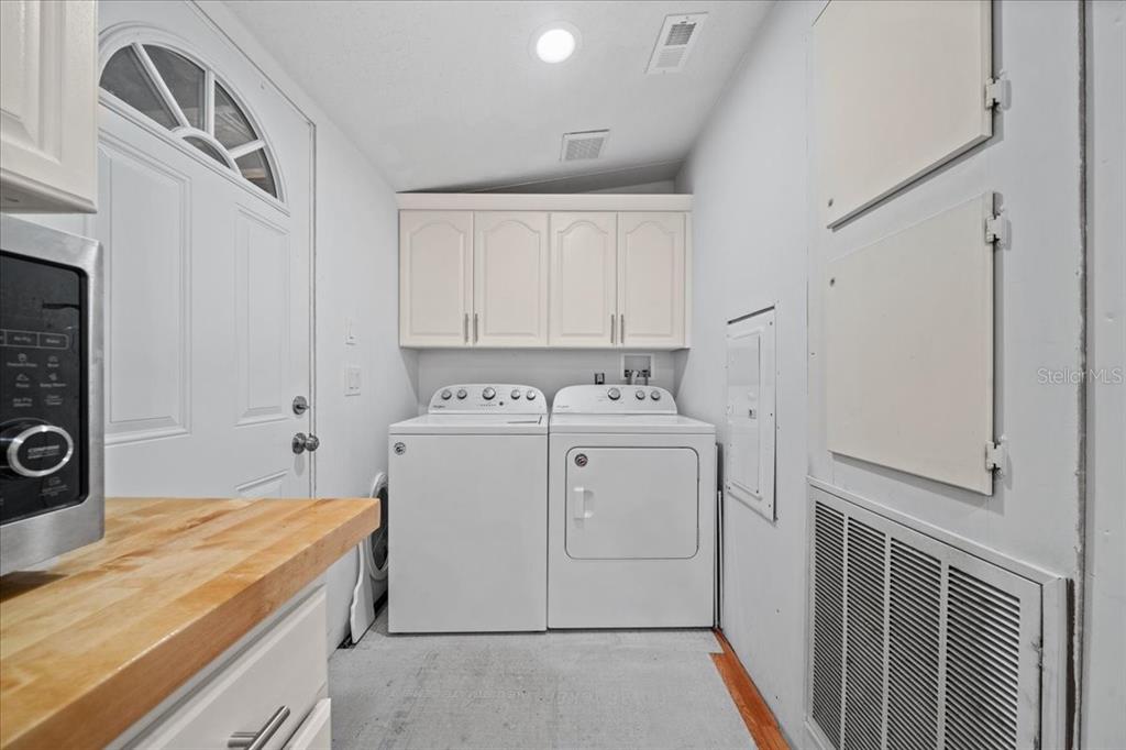 A laundry room features white cabinets, a washer and dryer, and a side exterior door — 13120 SW 90TH STREET, DUNNELLON, FL