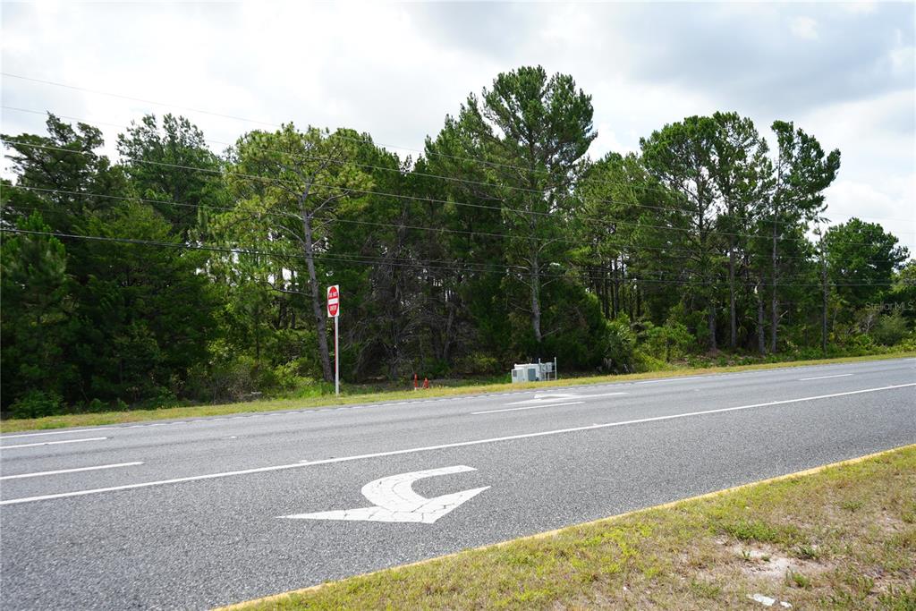 A paved road with a turn arrow leads to a wooded lot with a utility box — 18284 COMMERCIAL WAY, WEEKI WACHEE, FL