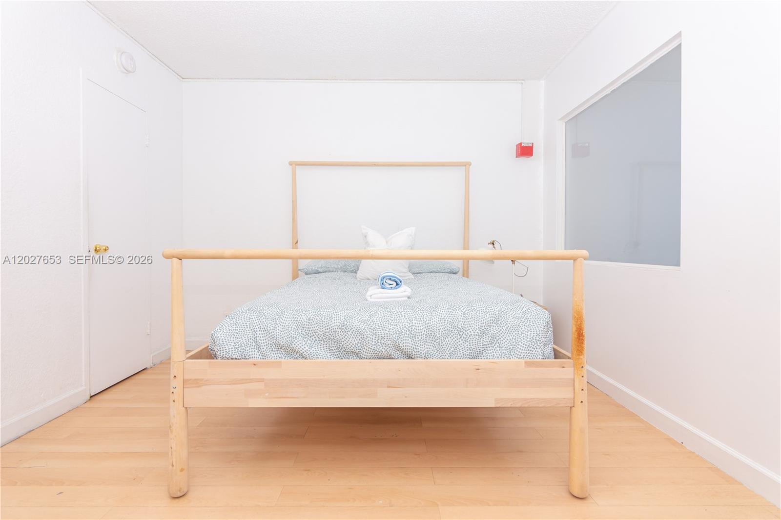 A bedroom features a light wood bed frame, light-colored wood flooring, and white walls — 5445 Collins Ave # 1105, Miami Beach FL 33140, MIAMI BEACH, FL