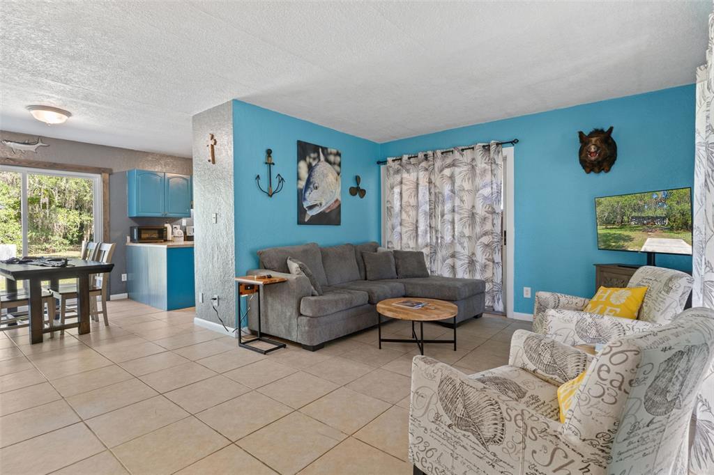 A living room with blue walls, a gray sectional sofa, and a patterned armchair — 8668 N ELMTREE AVENUE, CRYSTAL RIVER, FL