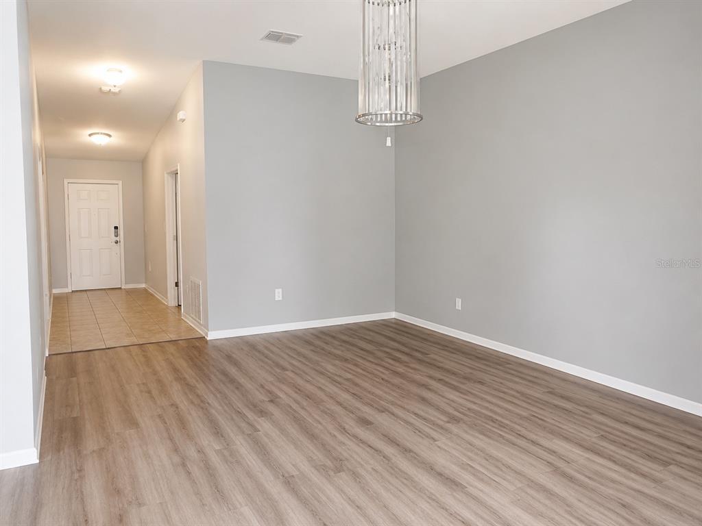 An interior view shows a dining area with wood-look flooring and a modern crystal chandelier — 18686 DOBSON DRIVE, HUDSON, FL