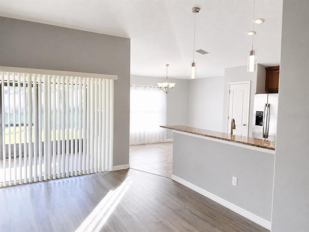 A kitchen with a breakfast bar overlooks a living area with vertical blinds — 18686 DOBSON DRIVE, HUDSON, FL