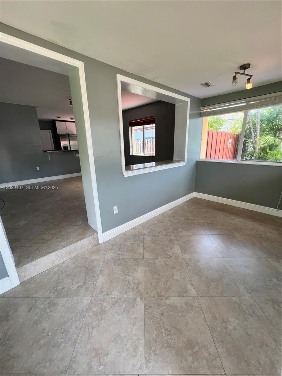 A dining area features light gray walls, tile flooring, and a pass-through window to the kitchen — 2502 Dewey St, Hollywood FL 33020, HOLLYWOOD, FL