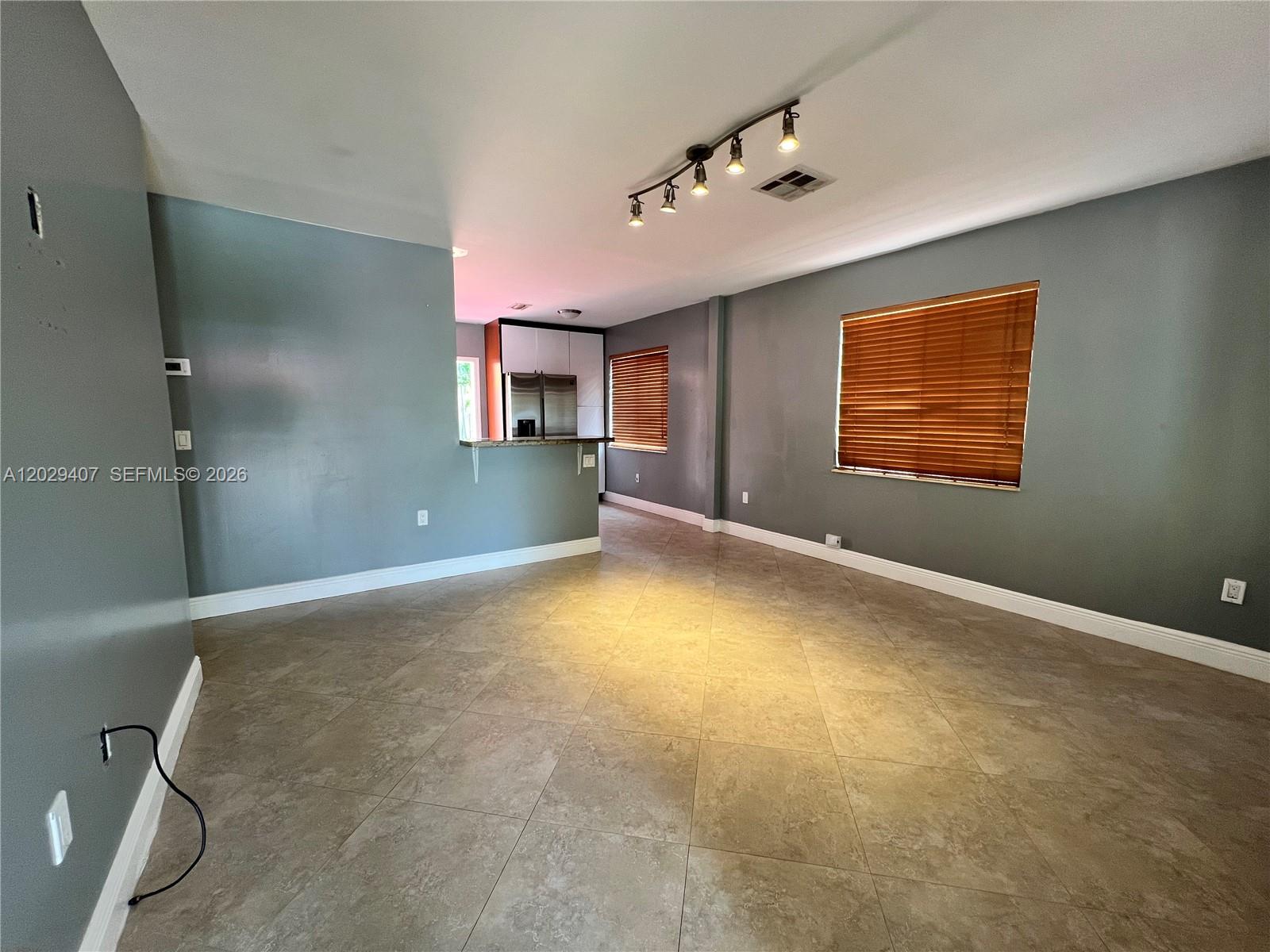 An open-concept living area features gray walls, tile flooring, and a pass-through kitchen — 2502 Dewey St, Hollywood FL 33020, HOLLYWOOD, FL