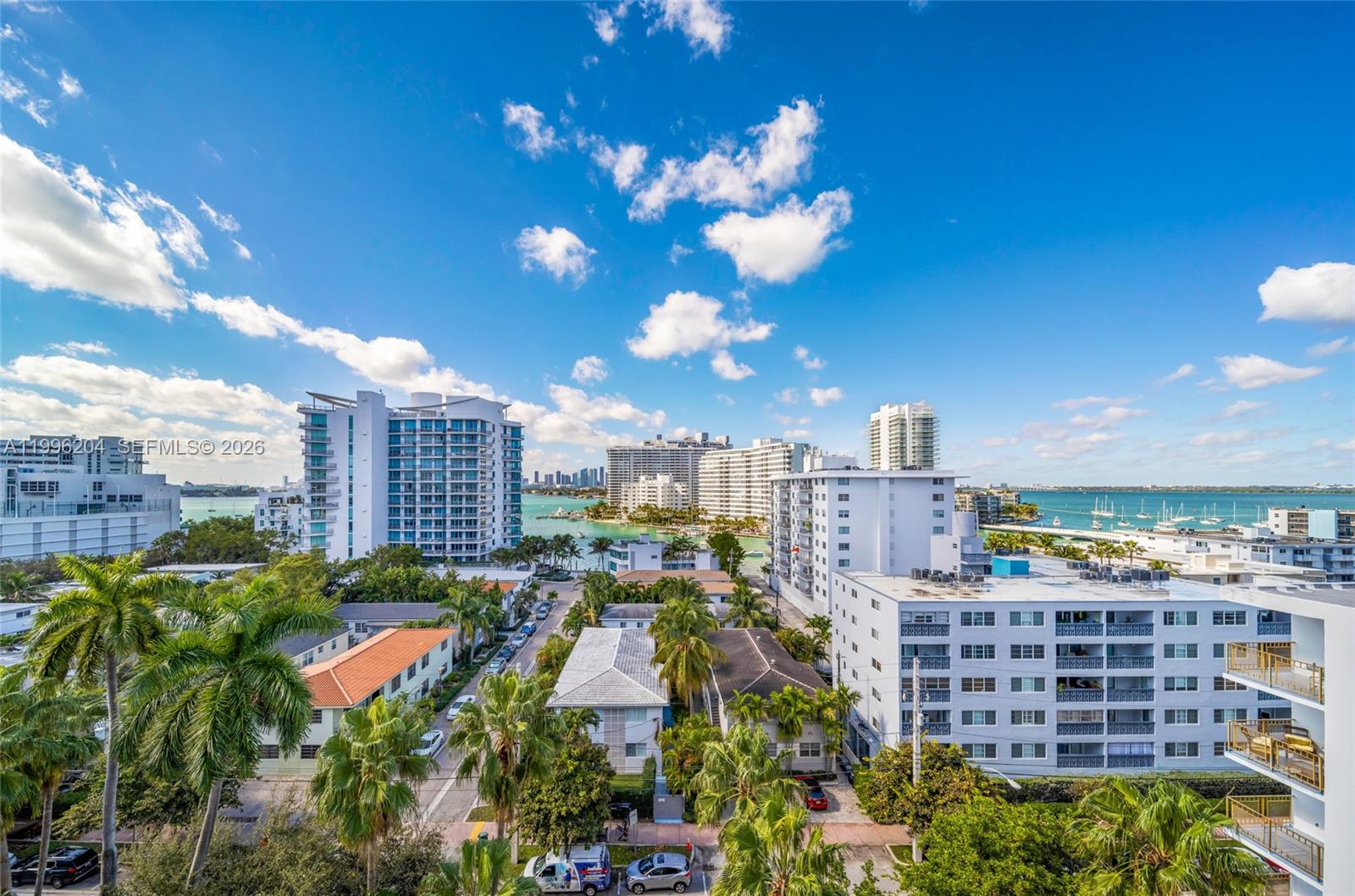 An elevated view of a coastal neighborhood with apartment buildings, palm trees, and the ocean — 1621 Bay Rd # 802, Miami Beach FL 33139, MIAMI BEACH, FL