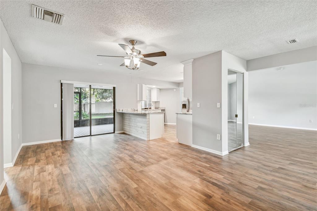 A living area with wood-look flooring, a ceiling fan, and an open kitchen with island — 1010 RIFLECREST AVENUE, VALRICO, FL